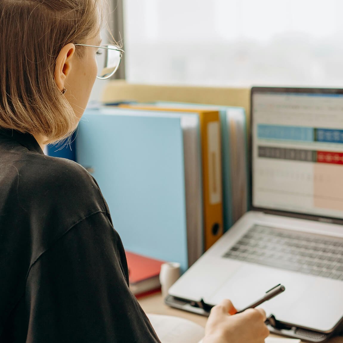 Professionista in ufficio che consulta documenti tecnici accanto a un monitor
