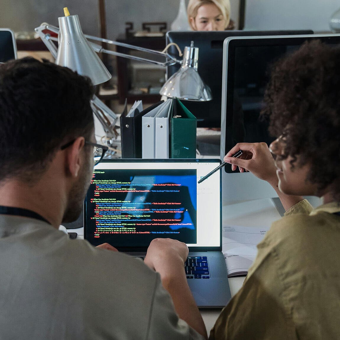 Due programmatori analizzano righe di codice software su un monitor durante una sessione di lavoro