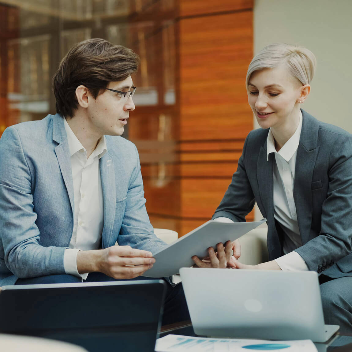 Professionisti in ufficio che discutono una strategia analizzando dati su un tablet e un laptop