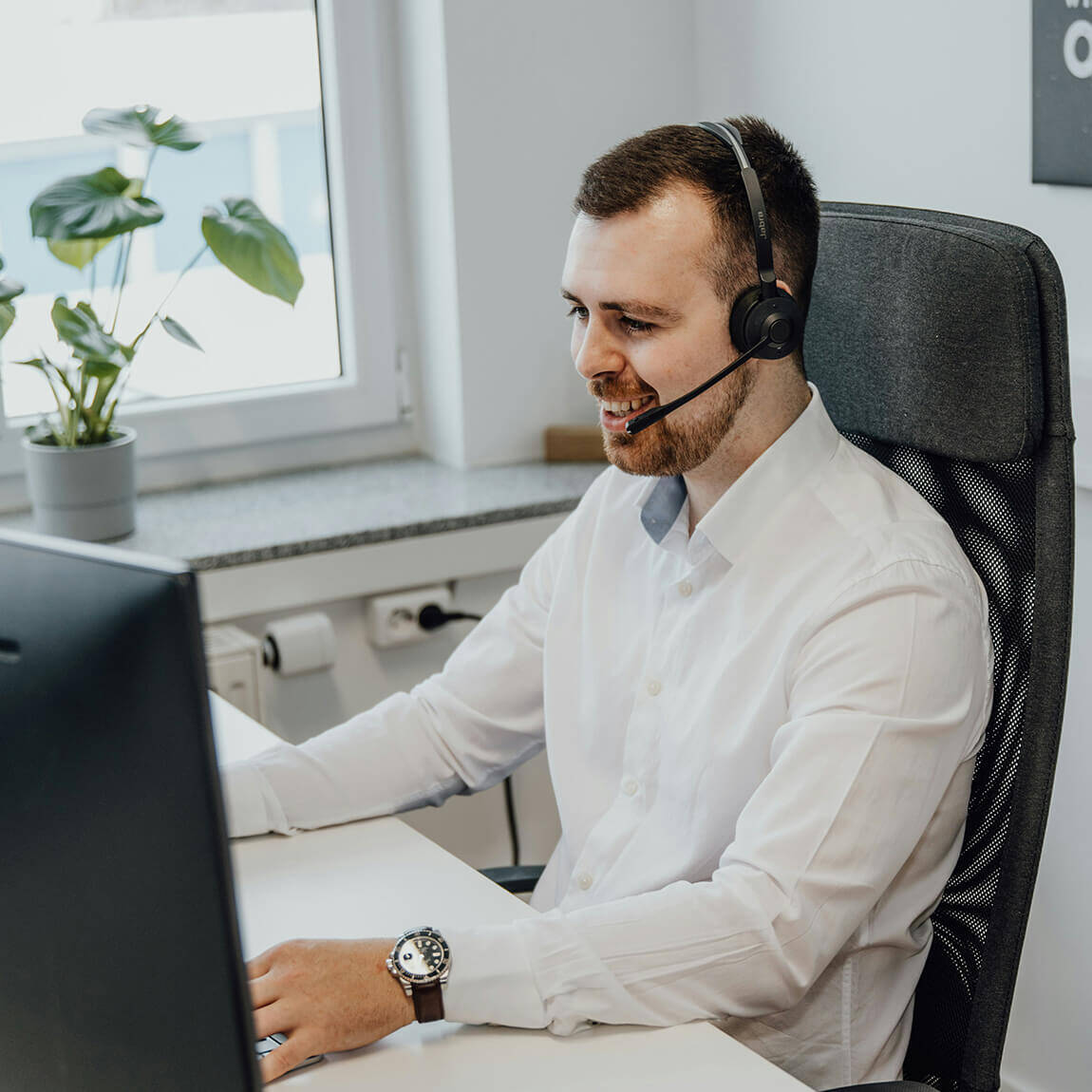 Operatore call center con cuffie che sorride mentre utilizza il sistema di gestione appuntamenti